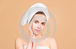 Beauty face of a cheerful attractive girl with towel on head, isolated. Moisturized healthy skin, morning spa, beauty