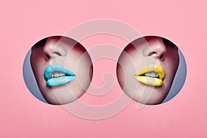 Beauty face makeup plump lips young two girls in round hole pink paper. Woman with beautiful makeup, plump lips yellow and blue in