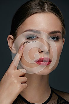 Beauty face makeup. Woman model with beauty word on skin