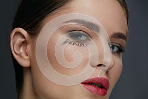 Beauty face makeup. Woman model with make-up and word on skin