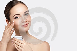 Beauty face model. Beautiful Woman with healthy smooth facial clean skin holding bottle cosmetic cream