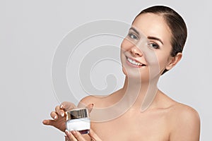 Beauty face model. Beautiful Woman with healthy smooth facial clean skin holding bottle cosmetic cream