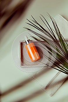 Beauty face serum flatlay with blurred palm leaves on the foreground, copy space, earthy tones