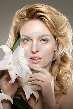 Beauty face woman, flowers, lily. Girl healthy model in spa salon. Cream treatment products. Facial skin terapy photo