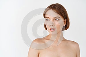 Beauty face. Young beautiful woman with naked shoulders, natural smooth and healthy facial skin, looking away at empty
