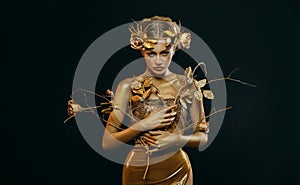 Beauty fantasy woman, face in gold paint. Golden shiny skin. Fashion model girl, image goddess. Glamorous crown, wreath