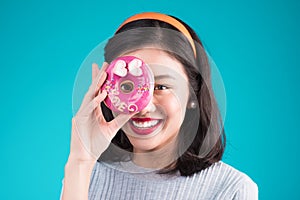 Beauty fashion ASIAN model girl taking colorful donut over blue
