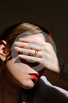 Beauty fashion female model touching her face wearing golden ring. Creative image. Jewellery concept.