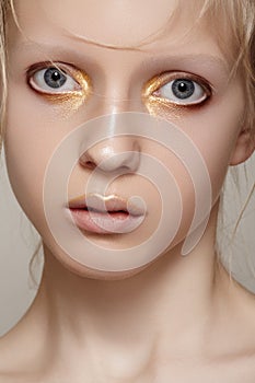 Beauty & fashion. Girl model face with bright holiday gold make-up, clean skin