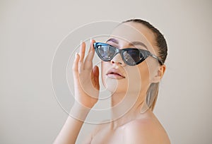 Beauty fashion model girl with brown hair wearing stylish sunglasses touches