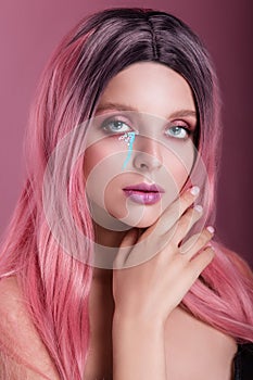 Beauty fashion model girl with colorful dyed pink hair and creative make-up on pink backround