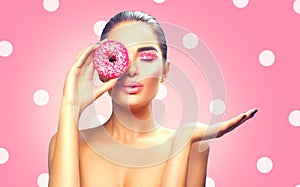 Beauty fashion model girl holding sweet pink colorful donut