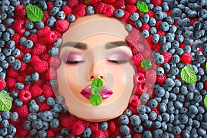 Beauty fashion model girl lying in fresh ripe berries. Face in colorful berries closeup. Beautiful makeup, juicy and lips