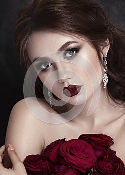 Beauty Fashion Model Girl Portrait with Red Roses. Lips and Nails. Beautiful Luxury Makeup Hair Manicure Vogue Style