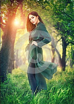 Beauty fashion model girl posing over blooming trees, enjoying nature in spring apple orchard