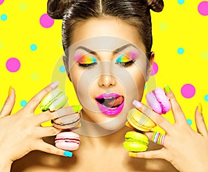 Beauty fashion model girl taking colorful macaroons