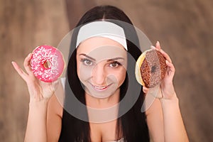 Beauty fashion model girl taking sweets and colorful donuts. Funny joyful styled woman with sweets on wood background. Diet, dieti