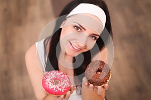 Beauty fashion model girl taking sweets and colorful donuts. Funny joyful styled woman with sweets on wood background. Diet, dieti