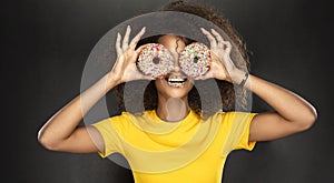 Beauty fashion model girl taking sweets and colorful donuts. Funny joyful Vogue styled woman with sweets on pink background. Diet