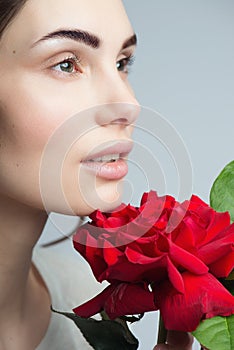 Beauty Fashion Model Woman face. Portrait with Red Rose flowers. Perfect skin.