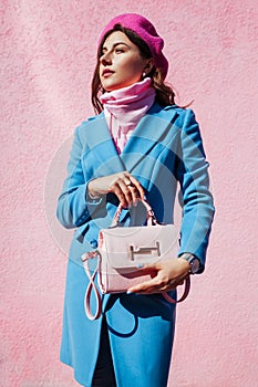 Beauty fashion model. Woman holding stylish handbag and wearing blue coat. Autumn female clothes and accessories