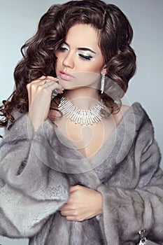 Beauty Fashion Model Woman in Mink Fur Coat. Winter Brunette Girl in Luxury clothes. Long wavy hair. Makeup. Jewelry.