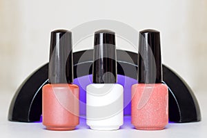 Beauty, fashion and Nail art concept. Manicure art cosmetic tools uv lamp and three bottles pink white beige gel nail polish. with