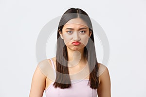 Beauty, fashion and people emotions concept. Close-up portrait of pouting upset cute asian girl grimacing, complaining