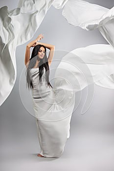 Beauty fashion photo of young beautiful girl in a flying white cloth.