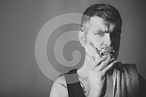 Beauty fashion portrait. Man cut beard and mustache with razor and shaving gel.