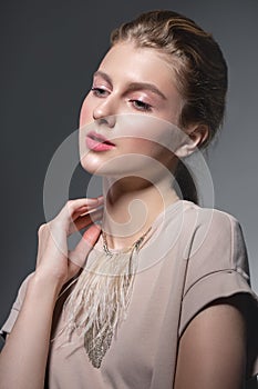 Beauty fashion portrait of a young beautiful girl posing in the Studio. Bright evening makeup, stylish clothes. Hand touches