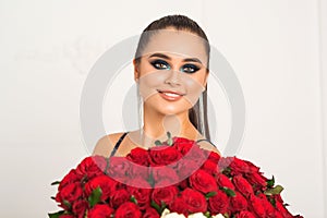 Beauty fashion sensual girl with big bouquet of red roses. Glamour sexy woman with fashion bright makeup. Valentine`s day
