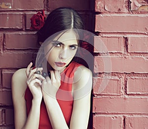 Beauty and fashion, spanish woman with fashionable makeup and rose flower in hair, girl in red dress on brick wall