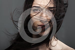 Beauty fashion studio portrait of a beautiful young girl with windy hair in front of her face