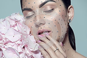 Beauty fashion Woman face decorated with gem stones, crystals. Closeup Portrait with Hydrangea. Model girl with holiday makeup