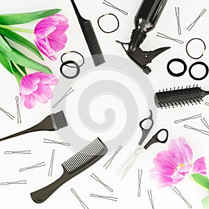 Beauty frame with hairdresser tools - spray, scissors, combs, barrette and tulips flowers on white background. Flat lay, top view