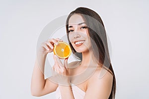 Beauty funny portrait of happy smiling asian woman with dark long hair with oranges in hands on white background isolated