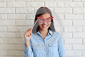 Beauty funny woman with paper glasses on stick smiling frankly