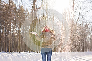Beauty Girl Blowing Snow in frosty winter Park. Outdoors. Flying Snowflakes.