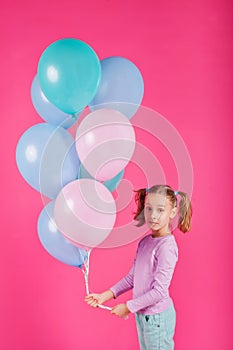 Beauty girl with colorful air balloons laughing over pink background. Beautiful Happy Young woman on birthday holiday party.