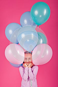 Beauty girl with colorful air balloons laughing over pink background. Beautiful Happy Young woman on birthday holiday party.