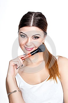 Beauty Girl make up artist with Makeup Brush. Bright Holiday Make-up for Brunette Woman with Brown Eyes. Beautiful Face. Makeover