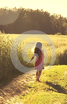 Beauty Girl Outdoors enjoying nature. Beautiful little girl in red dress running on the Spring Field. Toned