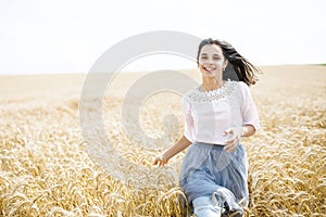 Beauty Girl Outdoors enjoying nature. Beautiful Teenage Model girl running on wheat field, Sun Light