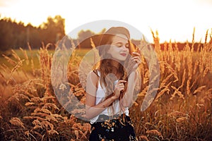 Beauty Girl Outdoors enjoying nature. Pretty Teenage Model in hat running on the Spring Field, Sun Light. Romantic