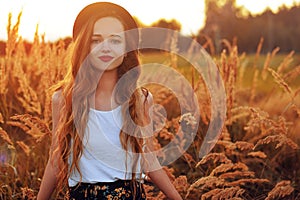 Beauty Girl Outdoors enjoying nature. Pretty Teenage Model in hat running on the Spring Field, Sun Light. Romantic