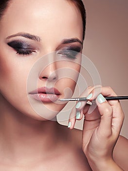 Beauty girl with Perfect make-up.Makeup artist applies lipstick.cosmetics
