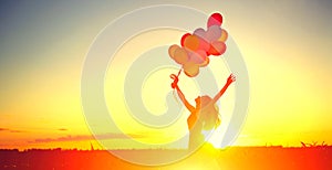 Beauty girl running and jumping on summer field with colorful air balloons