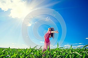 Beauty girl on summer field rising hands over blue clear sky