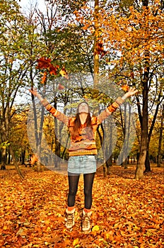 Beauty girl throwing leaves in autumn park